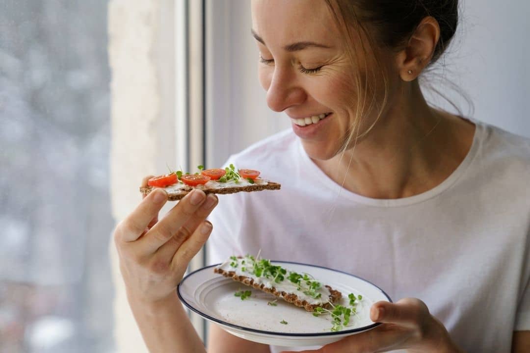 Glad-kvinna-som-ater-en-knackebrodsmacka